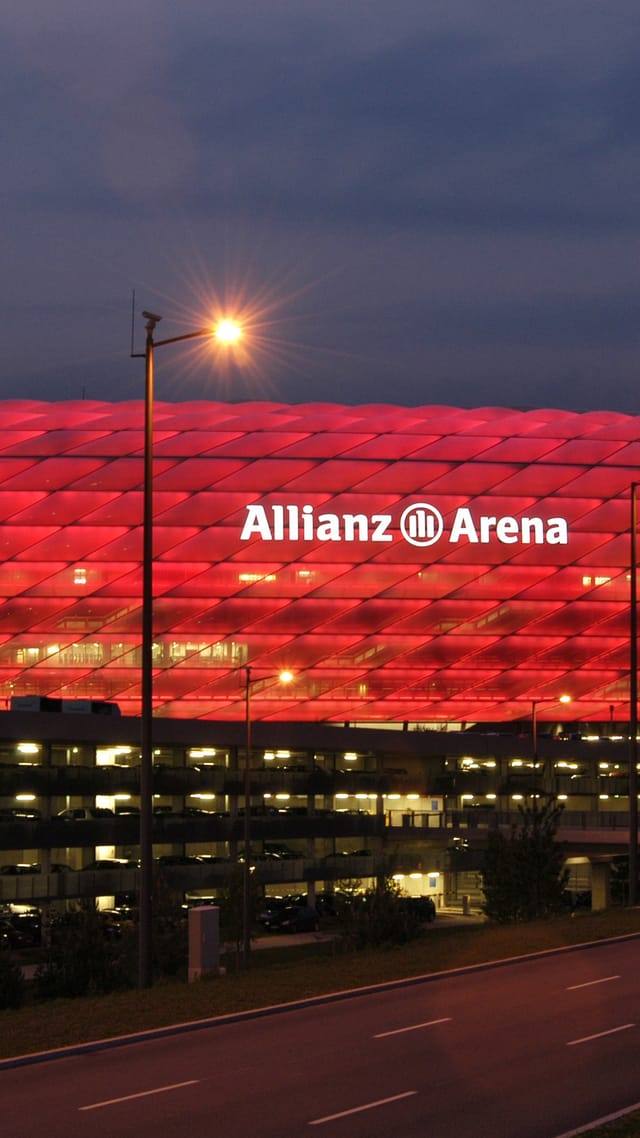 Allianz Arena - Fußballstadion mit rot beleuchteter Fassade bei Dämmerung.