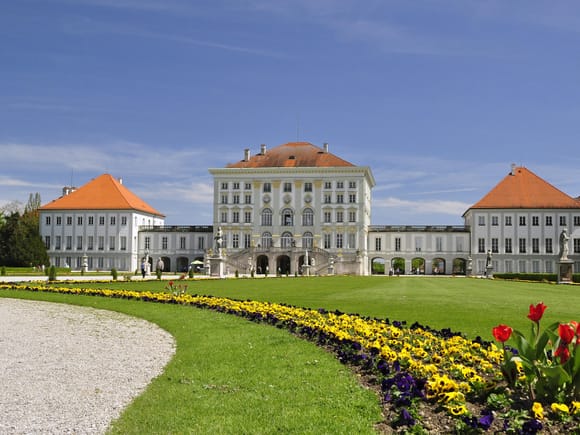 Schloss Nymphenburg München mit bunten Blumenbeeten im Vordergrund.