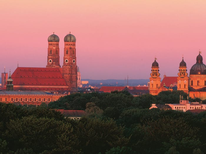 Münchner Skyline mit Frauenkirche und Theatinerkirche bei Sonnenuntergang.