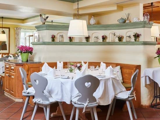 Heller Restaurantbereich mit weiß eingedeckten Tischen und Blumendekoration.