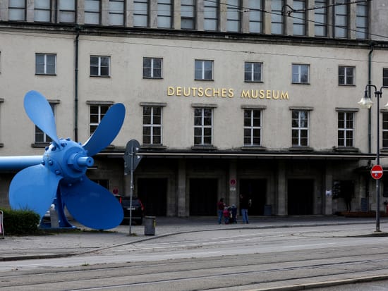 Haupteingang des Deutschen Museums München mit der markanten blauen Schiffsschraube als Skulptur davor.