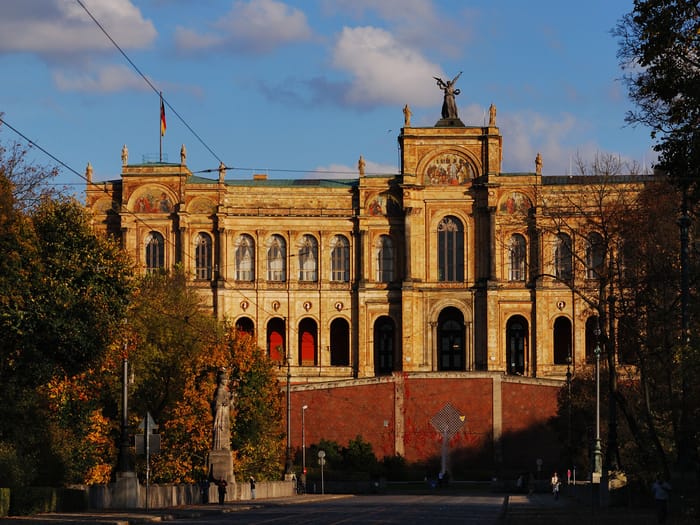 Maximilianeum München, historisches Gebäude im Herbstlicht mit Bayernflaggen.