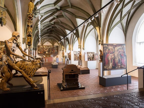 Der Kirchensaal des Bayerischen Nationalmuseums in München mit gotischem Gewölbe und ausgestellten sakralen Kunstwerken.