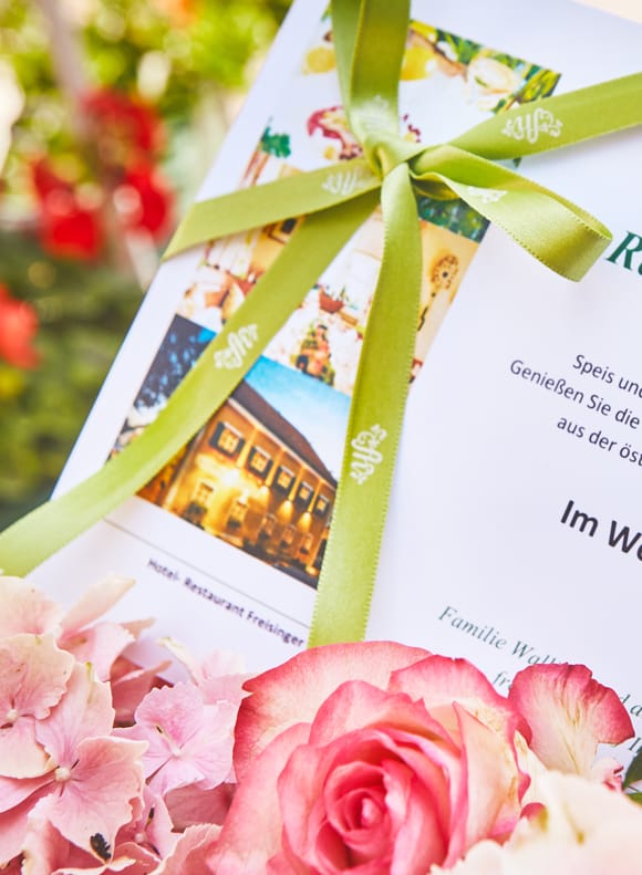 A restaurant voucher for 100 euros, tied with a bow and tucked into a bouquet of flowers.