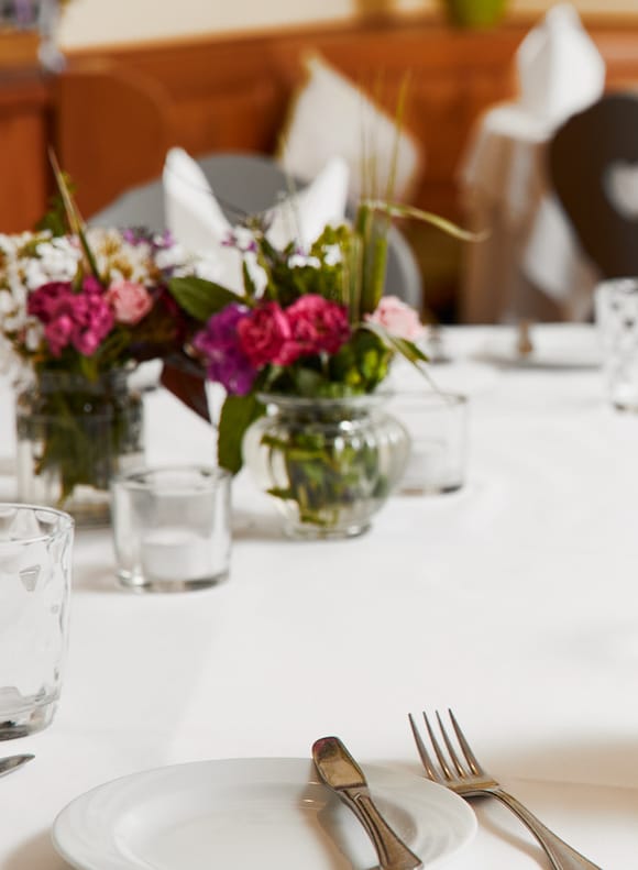 Elegantly set table with fine cutlery and floral accent.