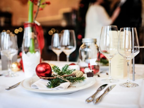 Festlich gedeckter Tisch mit weißem Porzellan, Kristallgläsern und weihnachtlicher Tischdekoration.