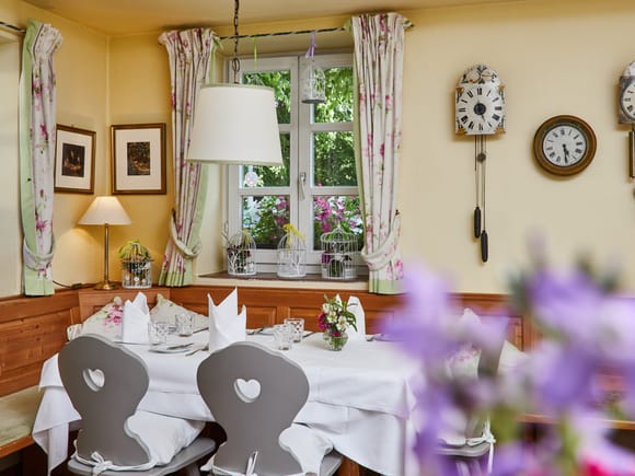Cozy dining nook with floral curtains and heart-back chairs.