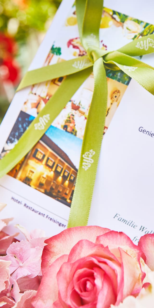 A restaurant voucher for 100 euros, tied with a bow and tucked into a bouquet of flowers.