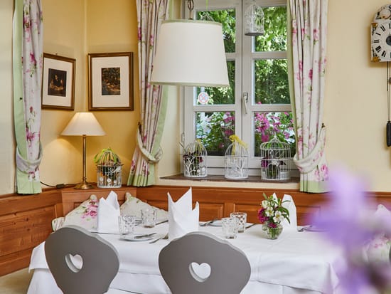 Cozy dining nook with floral curtains and heart-back chairs.