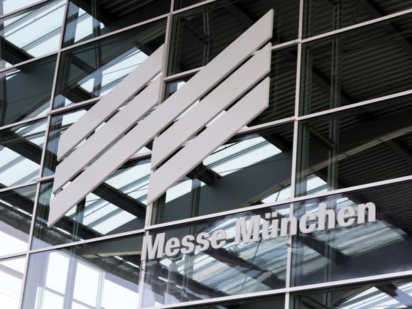 Schriftzug und Logo der Messe München an der Glasfassade des Messegeländes.
