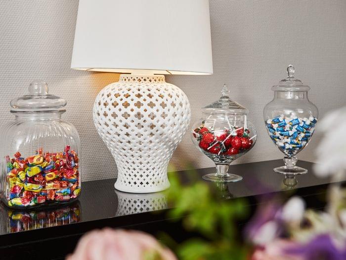 Kleine Naschstation in der Lobby im 1. Stock: Drei elegante Glasgefäße mit bunten Bonbons, Erdbeer-Lollipops und Kaubonbons laden Gäste zum Zugreifen ein – eine charmante Geste der Gastfreundschaft.