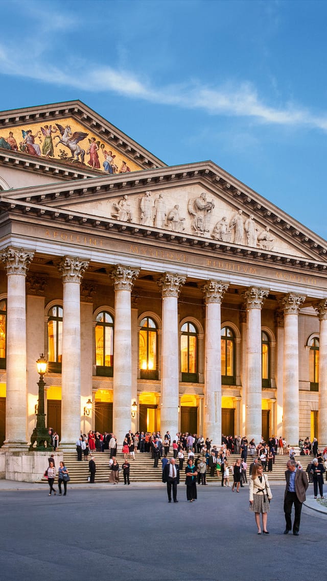Bayerische Staatsoper in München, klassizistische Fassade mit beleuchteten Säulen am Abend.