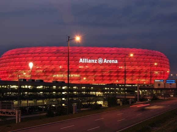 Allianz Arena - Fußballstadion mit rot beleuchteter Fassade bei Dämmerung.
