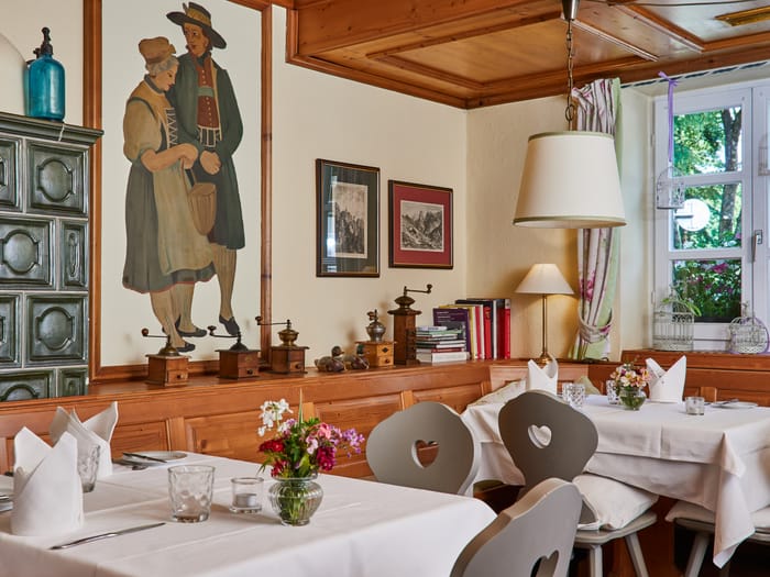 Traditional dining room with tiled stove and set tables.