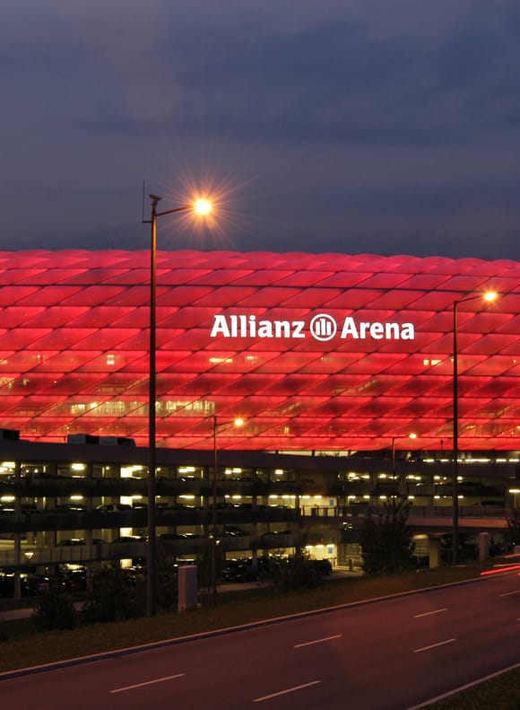Allianz Arena - Fußballstadion mit rot beleuchteter Fassade bei Dämmerung.
