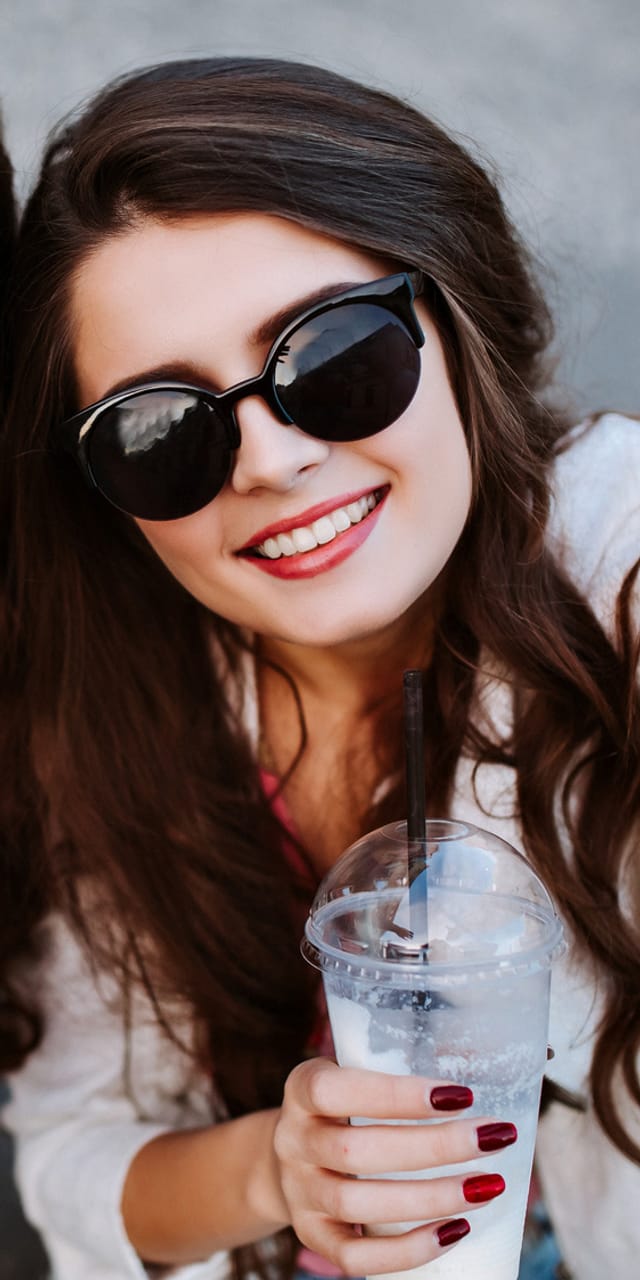 Two young women wearing sunglasses laughing and taking a selfie – carefree time with friends and city trip vibes.