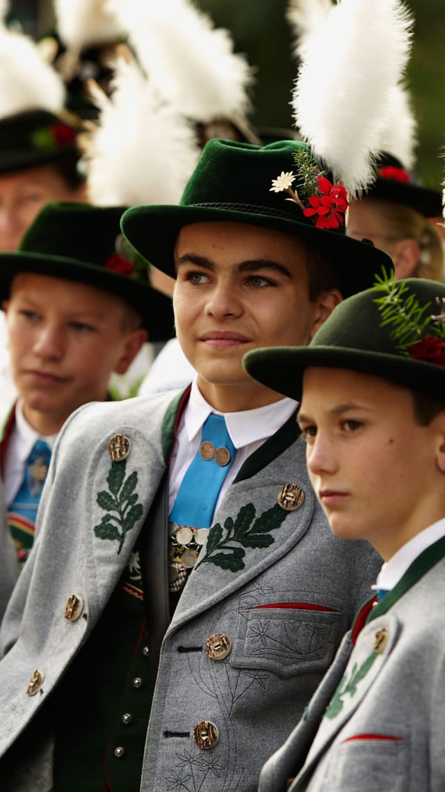 Junge Teilnehmer des Trachten- und Schützenzugs beim Münchner Oktoberfest, in traditioneller Tracht mit Federbüschen am Hut.