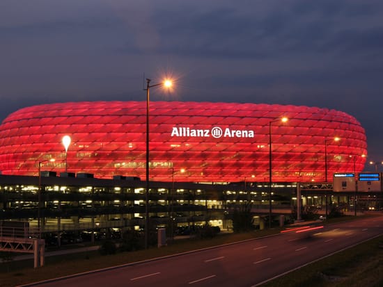 Allianz Arena - Fußballstadion mit rot beleuchteter Fassade bei Dämmerung.