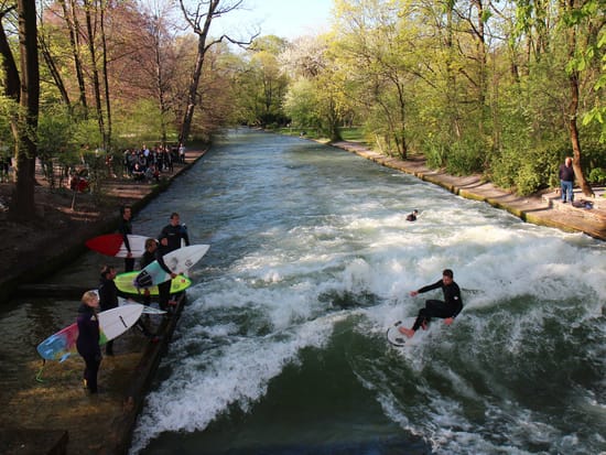 Mehrere Surfer und Zuschauer am Eisbach im Englischen Garten München.