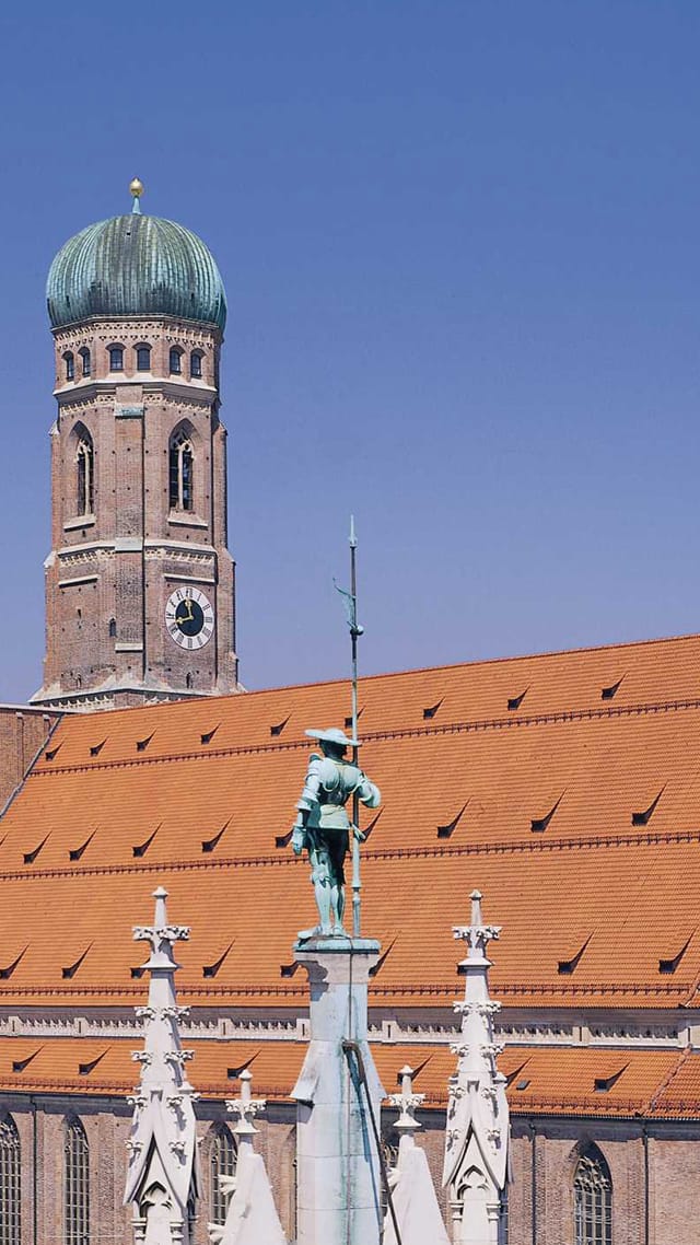 Türme der Frauenkirche München über den roten Dächern der Altstadt.