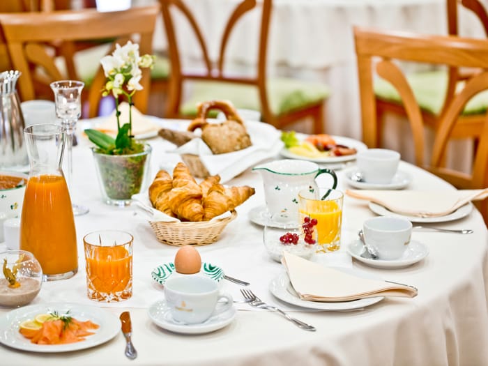 Elegant gedeckter Frühstückstisch mit Lachs, Ei, Säften und Gebäck.